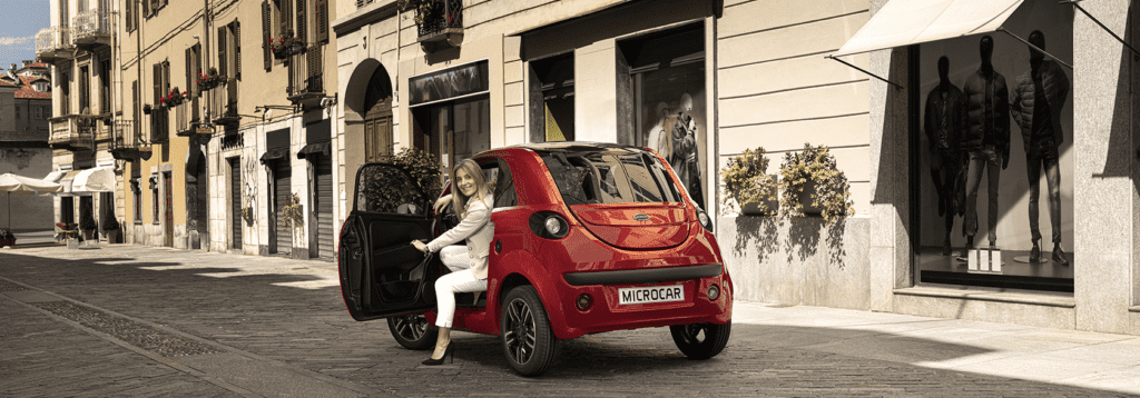 Microcar rood met dame op bestuurderstoel